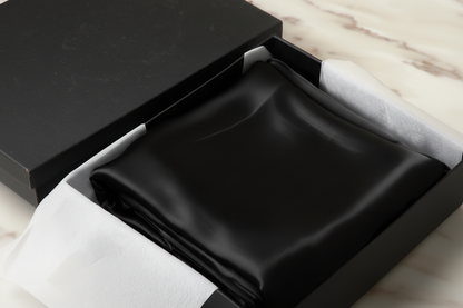 black satin pillowcase in a white box on a light wooden surface