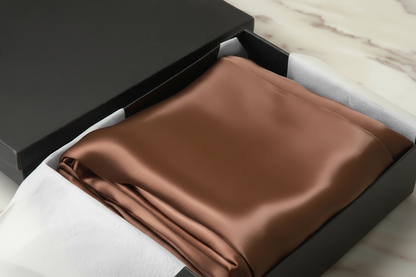 brown satin pillowcase in a box on a light wooden surface