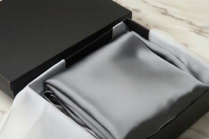 dark grey satin pillowcase in a box on a light wooden surface