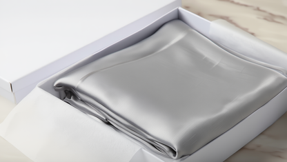 light grey pillowcase folded inside a white box on a light wooden surface