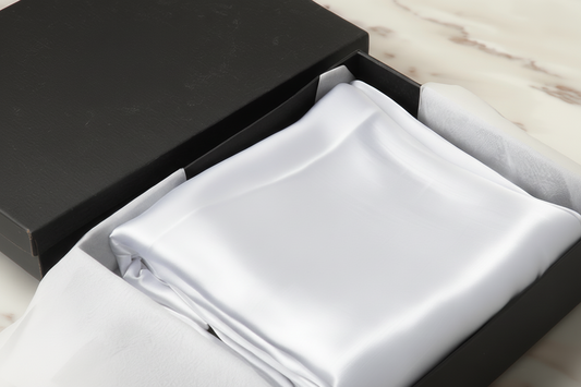 white satin pillowcase in a box on a light wooden surface
